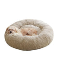 Small dog sleeping peacefully curled up inside a beige-grey fluffy round pet bed.