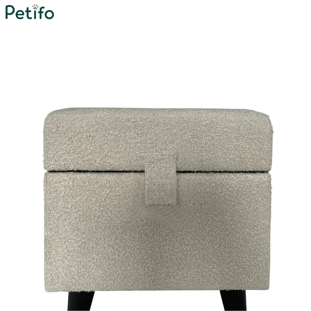  A closed cream-colored textured fabric pet pouffe with a central tab fastener.