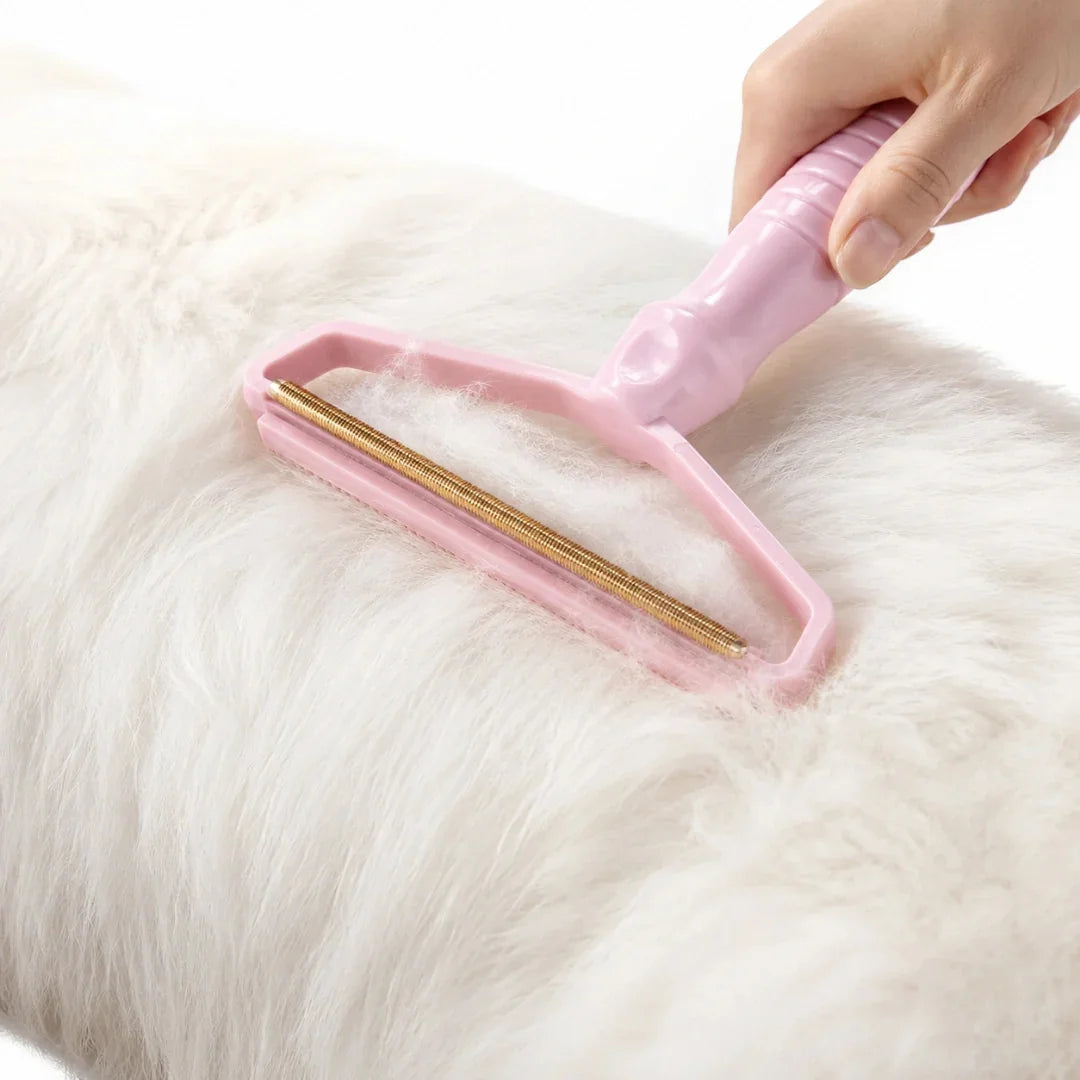Pink pet hair remover tool being used to gently brush thick white pet fur.