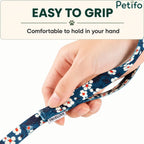 Hand holding the comfortable loop handle of a blue floral pattern dog leash.