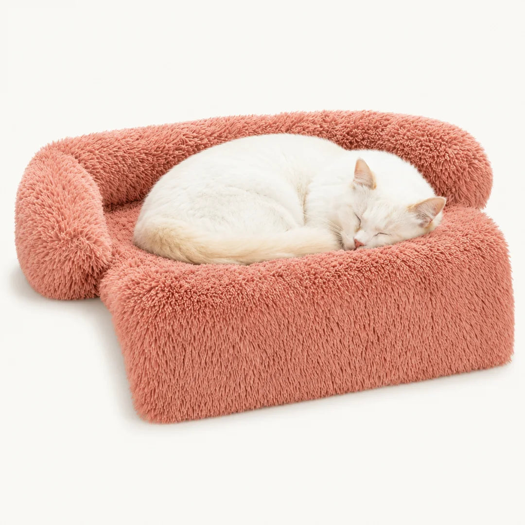 Soft pink plush pet sofa bed with a white cat sleeping peacefully.