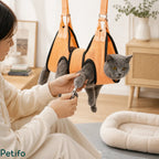 A person trimming the nails of a gray cat safely secured inside an orange Petifo grooming hammock.